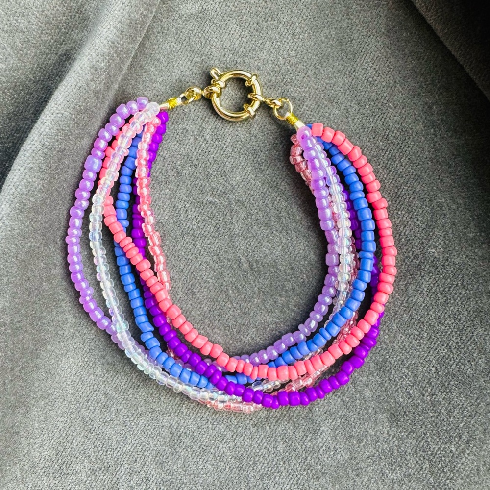Six strand hand beaded bracelet with 18k gold-plated hardware. 7”